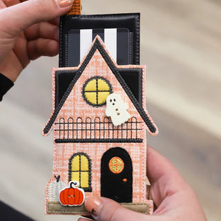 At the Layton In-Store Class, Kimberbell "The Stitching Hour" 2-Day Event (Aug 14-15, 2026), showcase your Halloween embroidery with a festive house-shaped card holder featuring a ghost, pumpkin, and cat.