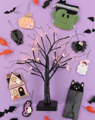 A black decorative tree with string lights, Halloween-themed ornaments, candy, and bat decor inspires your next project—perfect for the Kimberbell "The Stitching Hour" 2-Day Event on Aug 14-15, 2026 at Layton In-Store Class.