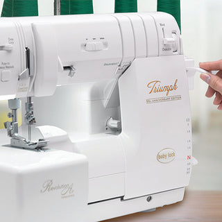 A person is holding a Baby Lock Triumph Serger sewing machine in front of a table.