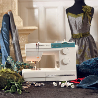A Husqvarna Viking Emerald 116 sewing machine on a table next to a mannequin.