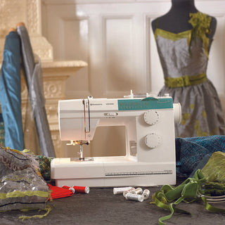 A Husqvarna Viking Emerald 118 sewing machine on a table next to a mannequin.