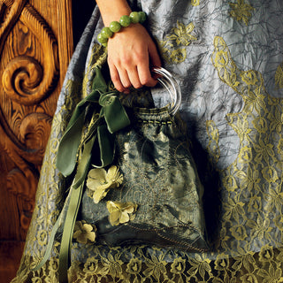 A woman wearing a Husqvarna Viking Emerald 116 dress holding a purse.