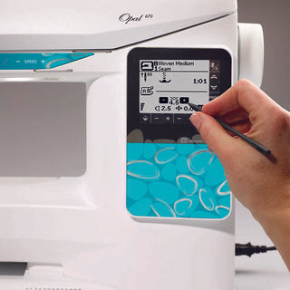 A person using a Husqvarna Opal 670 sewing machine with a blue screen.