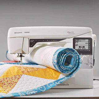 A Husqvarna Viking sewing machine with a quilt on top of it.