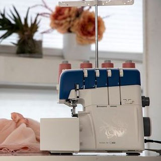 A Husqvarna Viking AMBER™ Air S | 400 sewing machine sits on a table next to a flower.