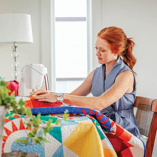 A woman is sewing a quilt on a Husqvarna Viking Brilliance 75Q.