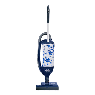 The Sew & Vac Sebo Felix Premium upright vacuum cleaner features a blue and white floral bag, top handle, and base wheels for multi-surface cleaning, shown against a white background.