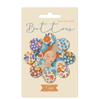 A set of eight blue and thistle wallflower buttons from Fabric by Tilda’s Tilda Wallflower Buttons (TIL400071) decorates a beige card labeled "Special Edition 2025"—ideal for adding a spring touch to your projects.