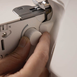 A person is using a Pfaff Admire Air 5000 sewing machine to adjust the button.