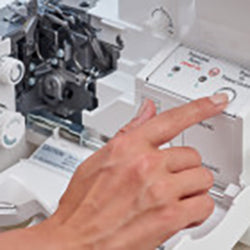 A person is pointing at a Baby Lock Acclaim Serger sewing machine.