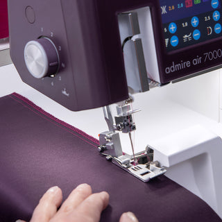 A person using a Pfaff sewing machine to sew a purple fabric.