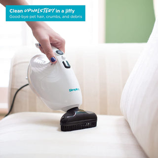 A person using a Simplicity FLASH Micro Vacuum to clean a couch.