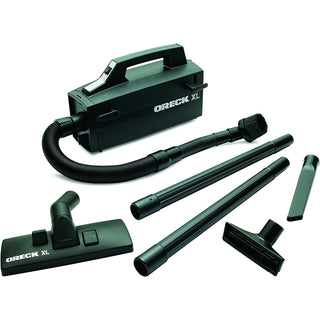 A black Oreck Super-Deluxe Compact Canister Vacuum Cleaner with a hose and attachments.