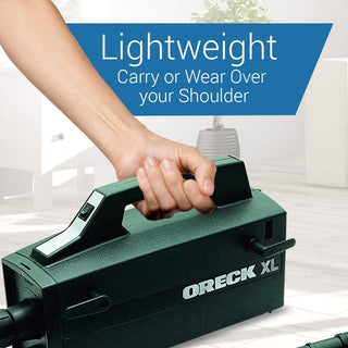 A person is holding an Oreck Super-Deluxe Compact Canister Vacuum Cleaner with the words lightweight carry or wear over your shoulder.