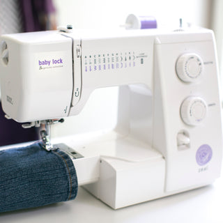 A Baby Lock Zeal Sewing Machine with a pair of jeans on it.