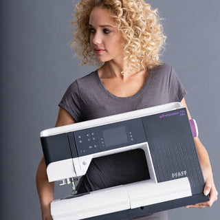 A woman with curly hair holding a PFAFF Quilt Expression 720 Sewing and Quilting Machine.