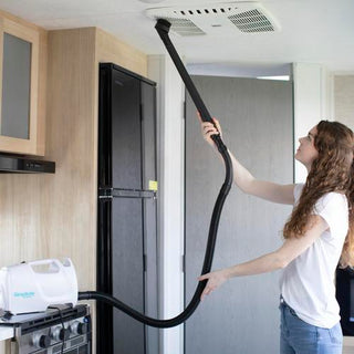 A woman using a Simplicity S100 Sport Portable Canister Vacuum in a kitchen.