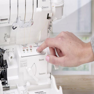 A person is using a Baby Lock Accolade Serger sewing machine to sew a piece of fabric.