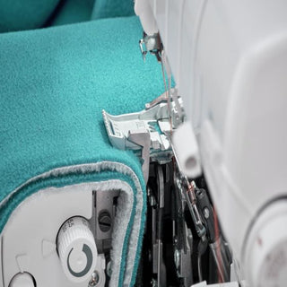 A close up of a Baby Lock Accolade Serger with a turquoise fabric.