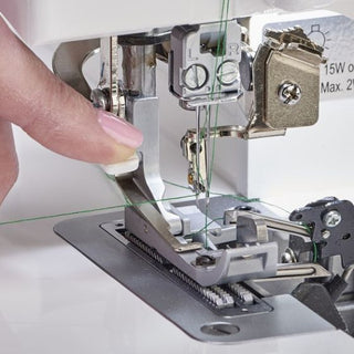 A person is using a Baby Lock Celebrate Serger sewing machine to sew a piece of fabric.