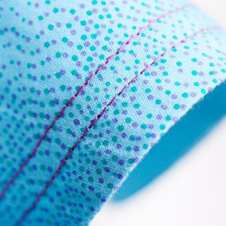 A close up of a Husqvarna Viking Huskylock S21 blue polka dot fabric.