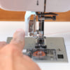 A person is using a Baby Lock Jazz II Sewing and Quilting Machine to sew a piece of fabric.