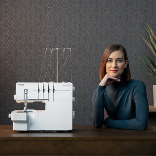 A woman posing in front of a Pfaff Hobbylock 2.5 sewing machine.