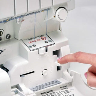 A person is using a Baby Lock Victory Serger sewing machine to sew a piece of fabric.