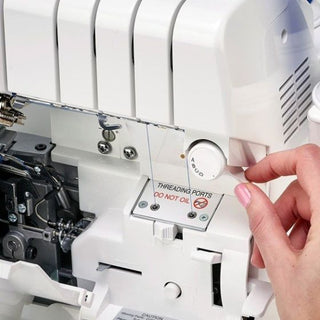 A person is using a Baby Lock Victory Serger sewing machine to sew a piece of fabric.