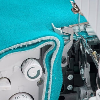 A close up of a Baby Lock Victory Serger with a blue fabric.
